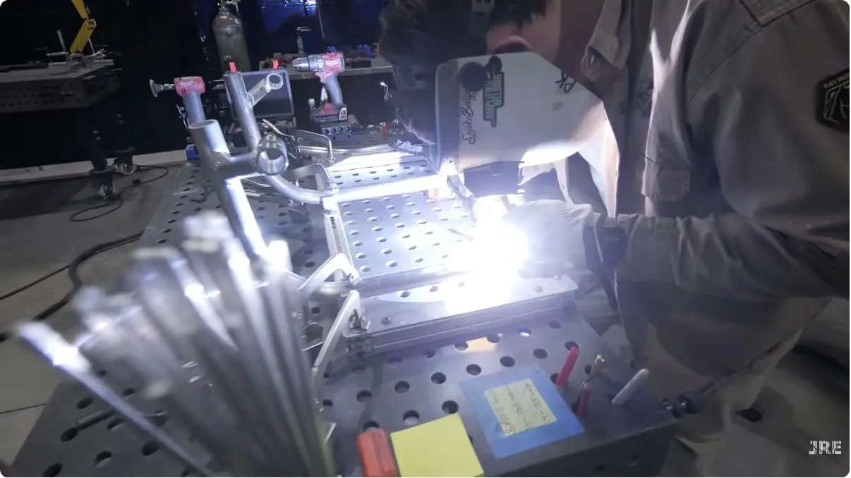 A welder works on a metal wheelchair frame in the Not A Wheelchair factory.