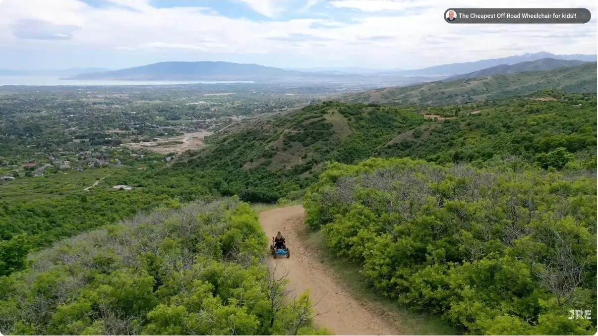 An off-road electric mobility device travels down a dirt trail above a valley.