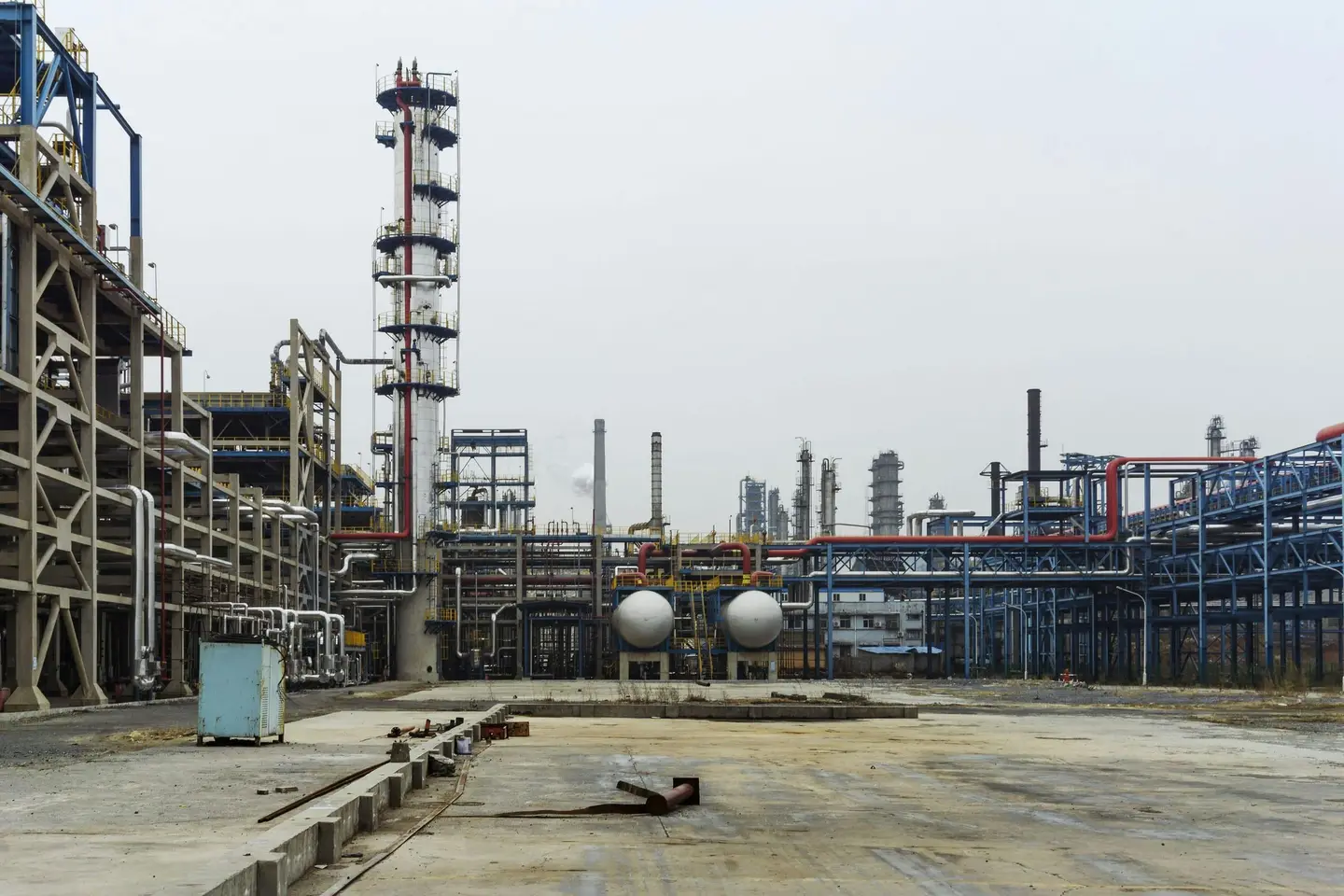 A dense industrial refinery with steel pipes, towers, and catwalks.
